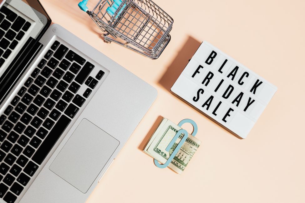Laptop and shopping basket beside a Black Friday sale sign
