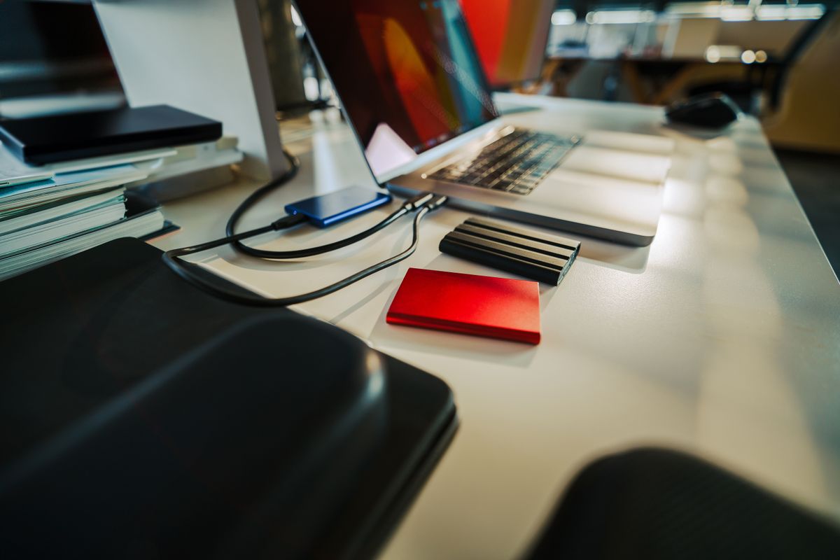 Several external hard drives on a desk beside a laptop, the usual answer to a full drive