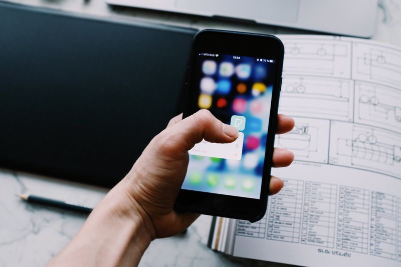 Hand holding a smartphone full of apps, where you'll find the Earth VPN app today