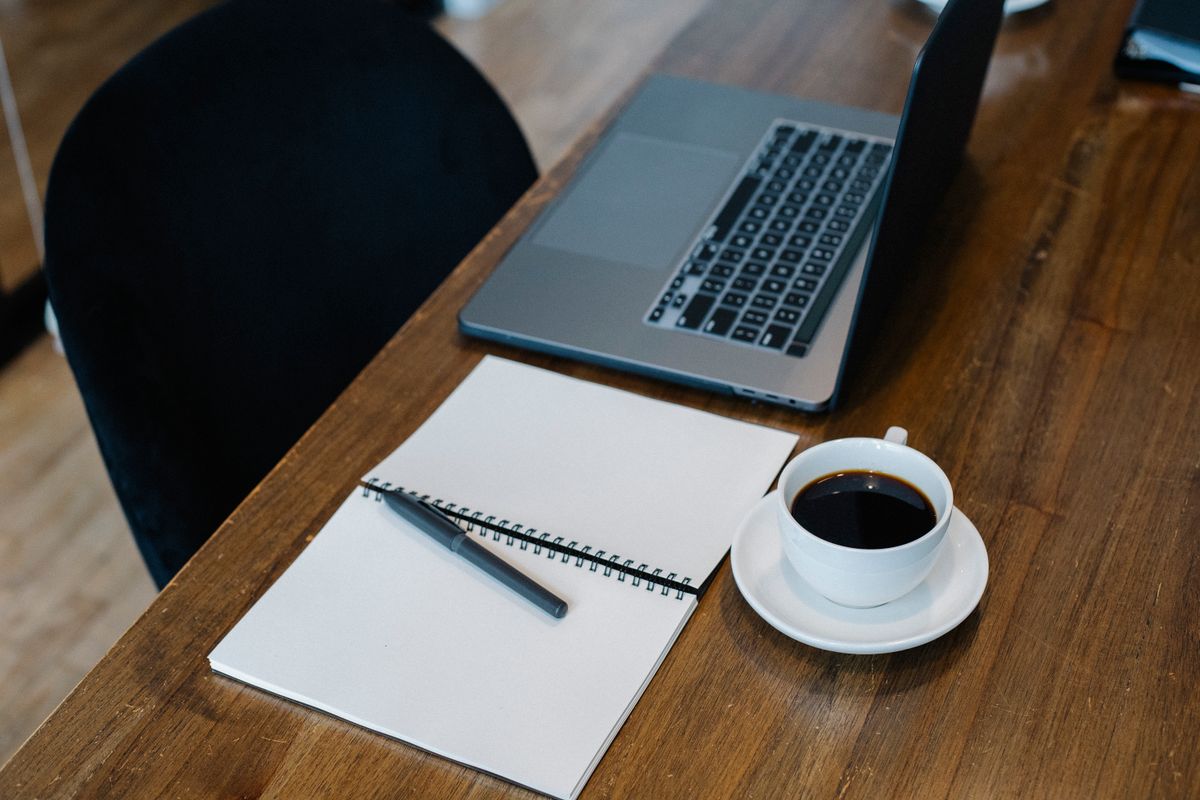 Laptop, notebook and coffee on a desk, ready to search free NZB indexers